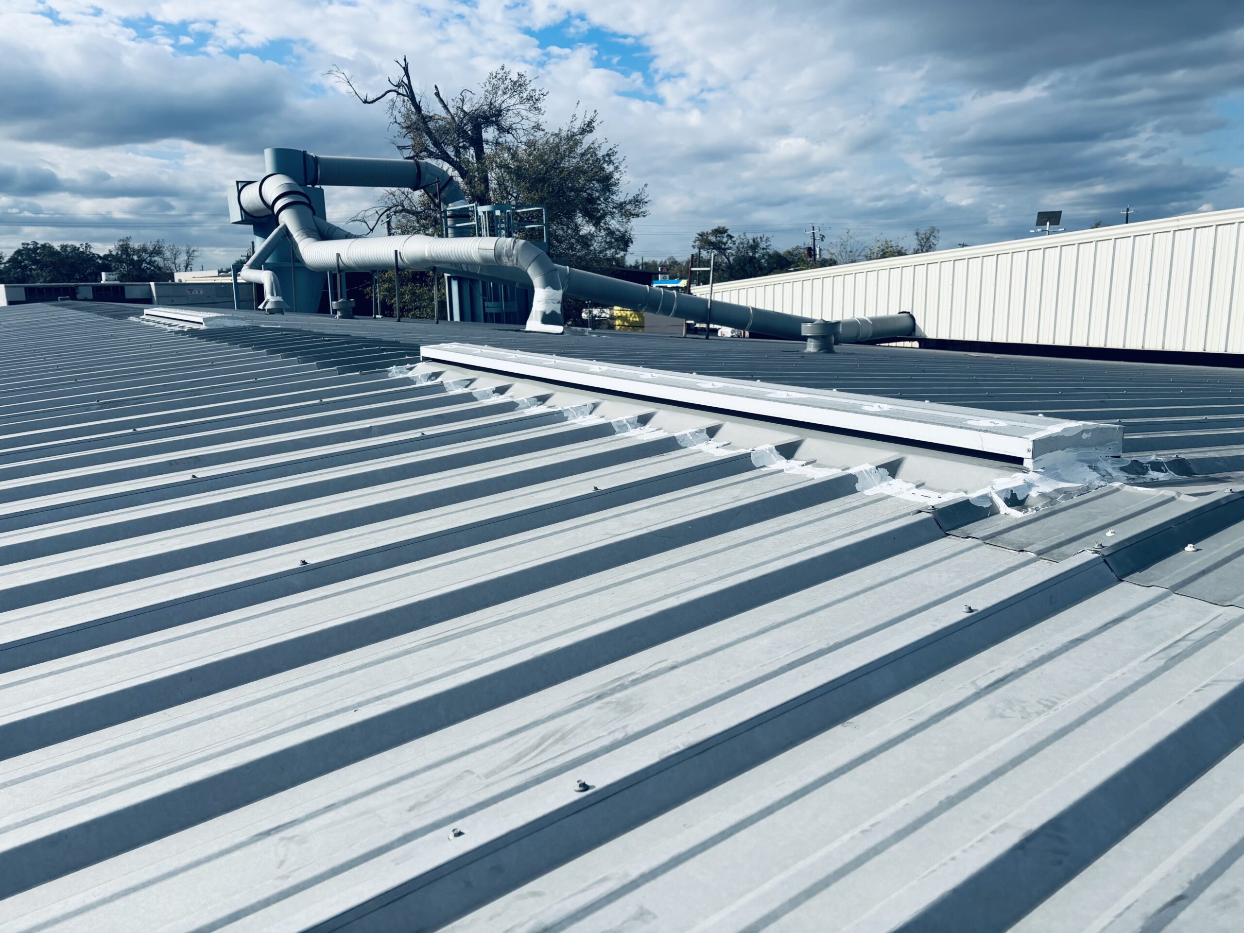 Corrugated metal roof with repaired seams and waterproofing, showcasing commercial roofing services by Pride Construction & Roofing in Houston.