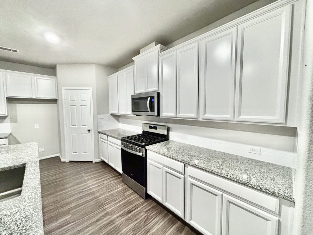 Modern kitchen remodel featuring white cabinetry, granite countertops, stainless steel appliances, and updated lighting in a stylish, functional layout.