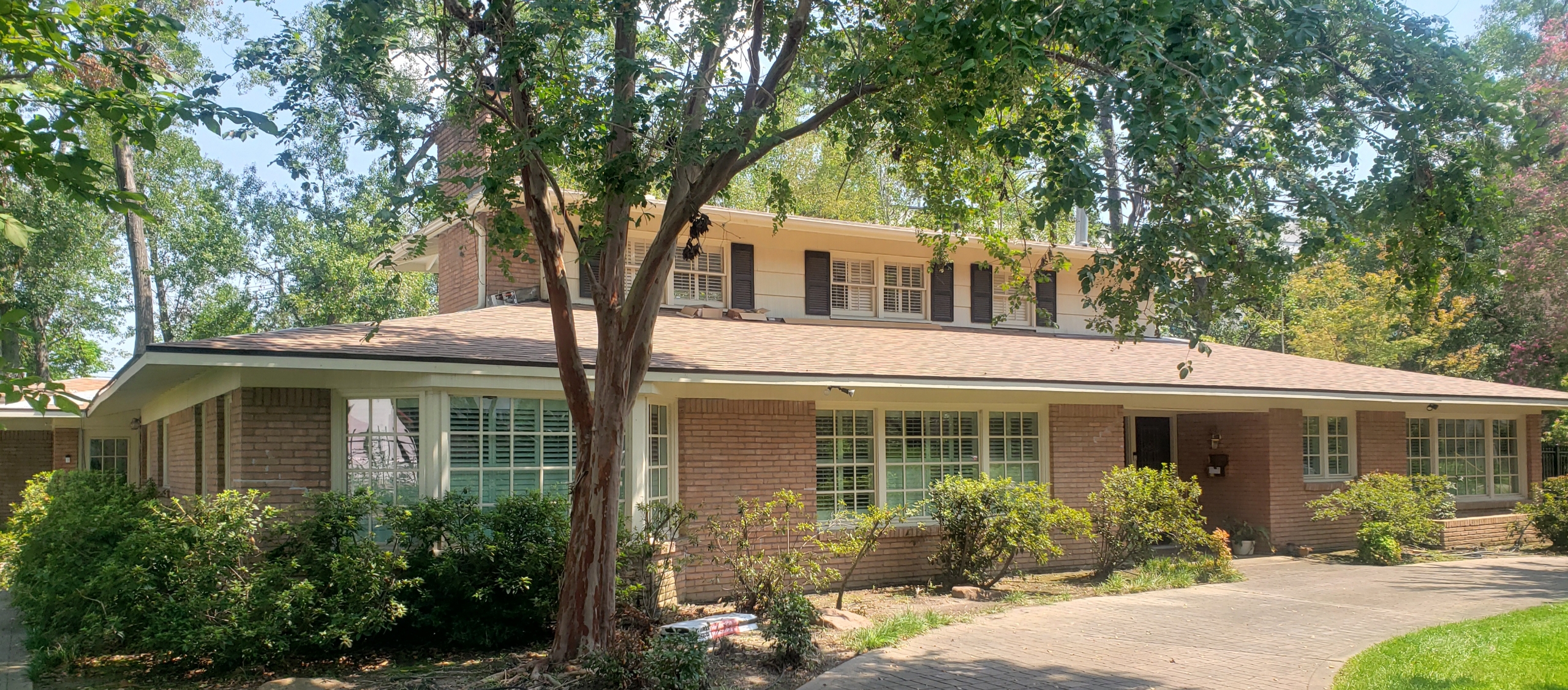 Residential home exterior showcasing a new roof, surrounded by greenery, highlighting Pride Construction & Roofing's remodeling expertise in Houston Heights.
