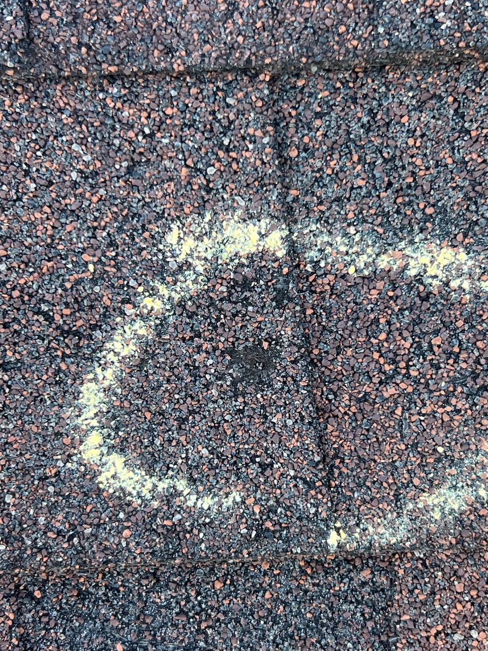 Roof shingles with yellow chalk markings indicating inspection areas for potential damage after recent storms in Houston.