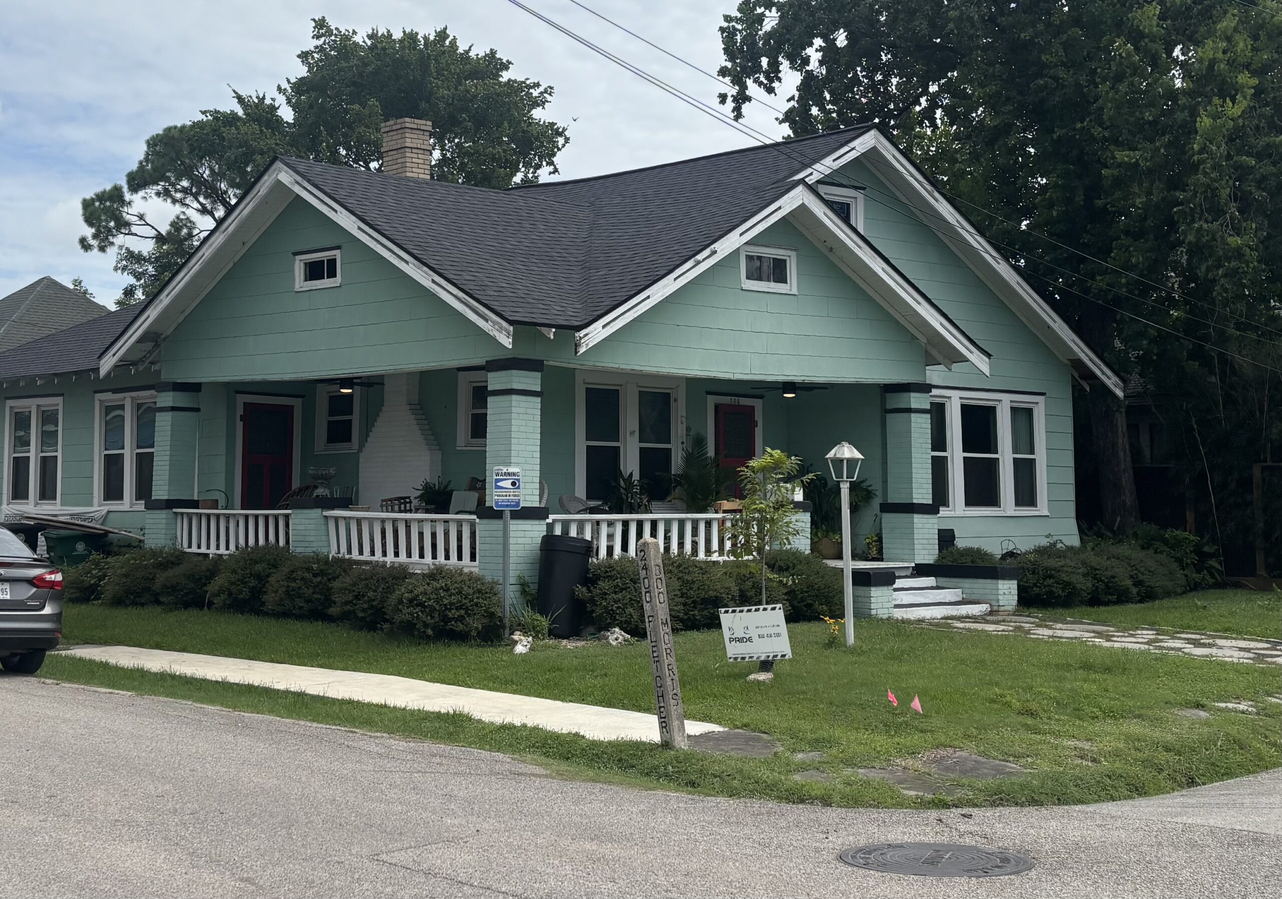 Stylish renovated house in Houston with mint green exterior, new roof, and updated landscaping, showcasing Pride Construction & Roofing's craftsmanship.